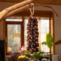 Large 96-seed Pala nut wind chime with peach pits and red beans on jute rope — flagship botanical sound healing and meditation decor