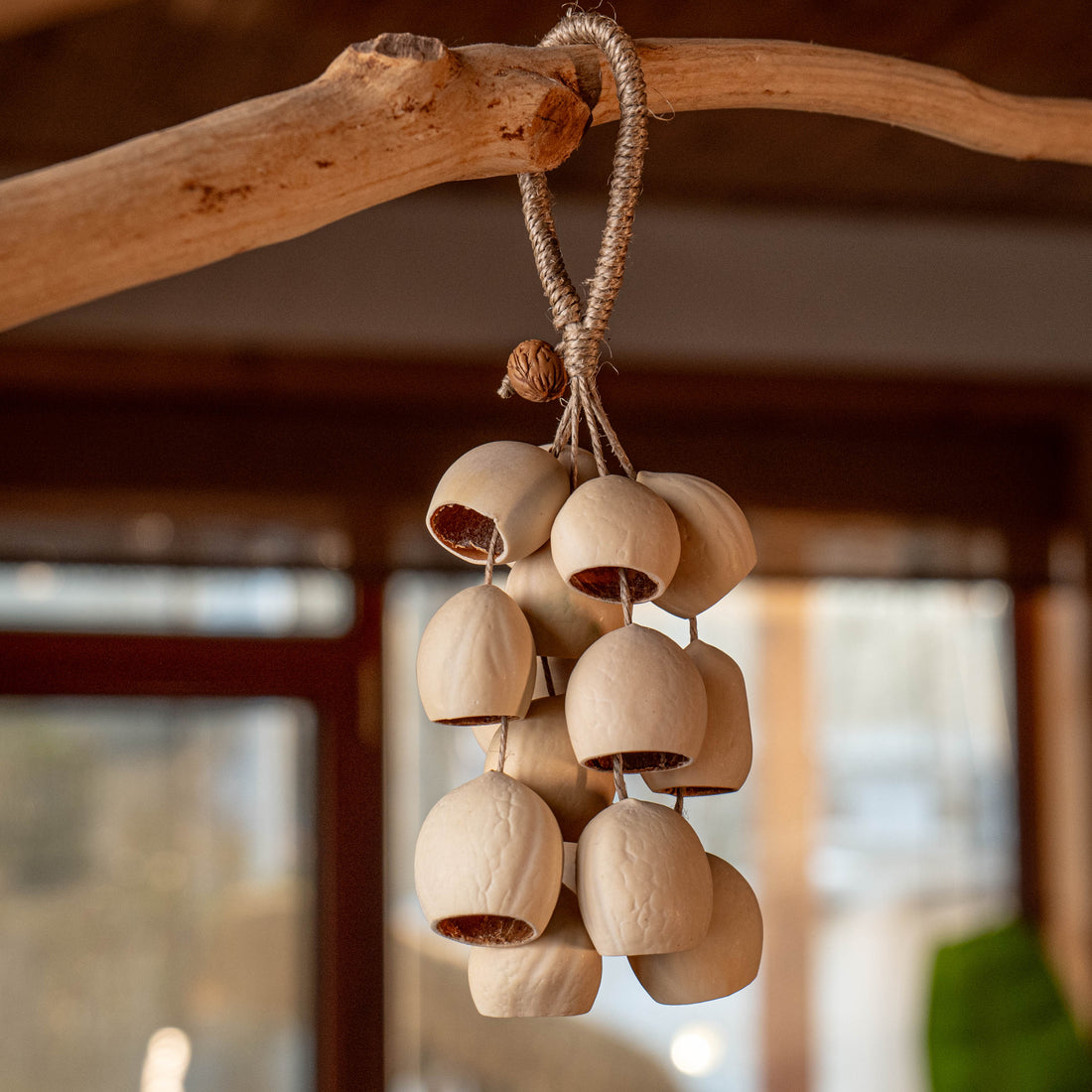 Handcrafted bag charm with 15 cream-colored Phoenix Egg botanical shells and peach pit accent on braided hemp loop — boho nature accessory
