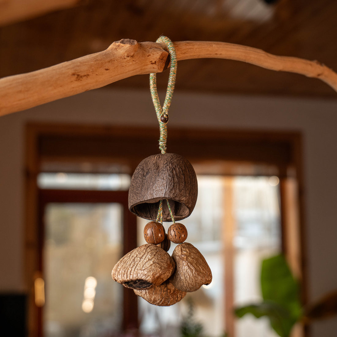 Handcrafted entryway door chime with dark Salin shell cap and Panji nut strikers on braided cord — natural boho home decor