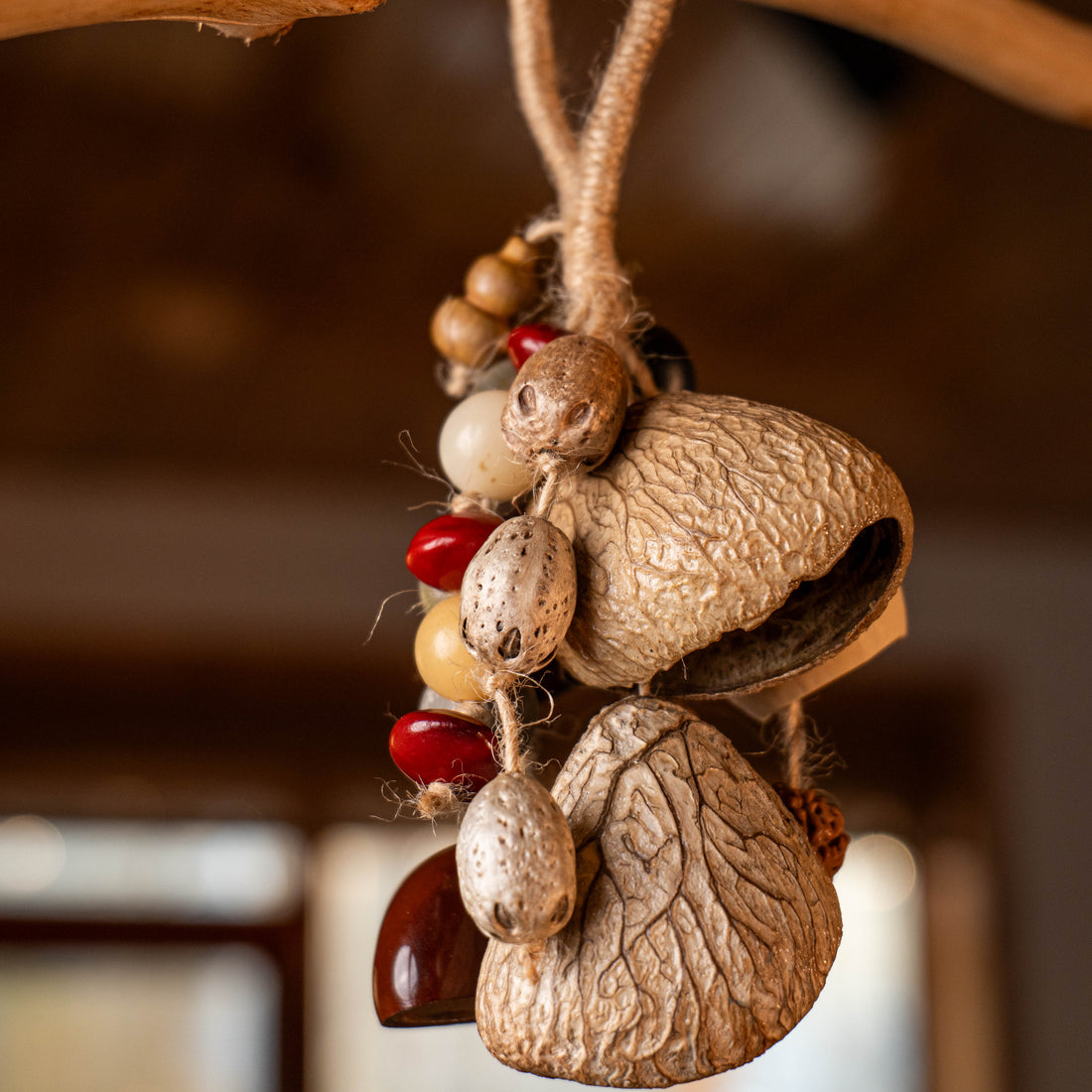 Handcrafted entryway door chime with Phoenix Egg shells, Panji nuts, Bodhi seeds and red beans on jute rope — natural boho home decor